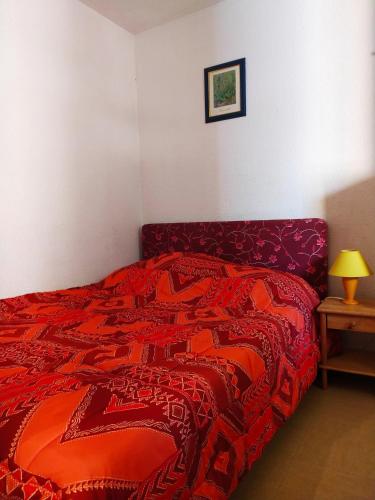 une chambre avec un lit avec une couette rouge dans l'établissement T2 au calme, entre mer et pinède., à Six-Fours-les-Plages