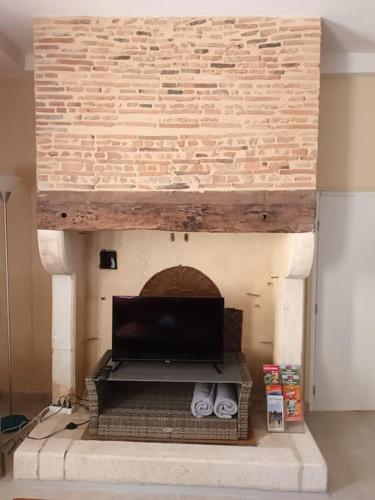 a fireplace with a tv on top of it at GÎTE AUX BOIS D'EN TEMPS in Lunas