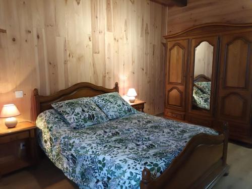 a bedroom with a bed and two night stands with lamps at GÎTE AUX BOIS D'EN TEMPS in Lunas