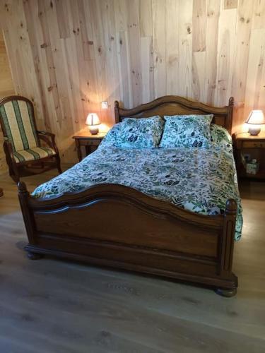 a bed in a bedroom with two tables and two lamps at GÎTE AUX BOIS D'EN TEMPS in Lunas