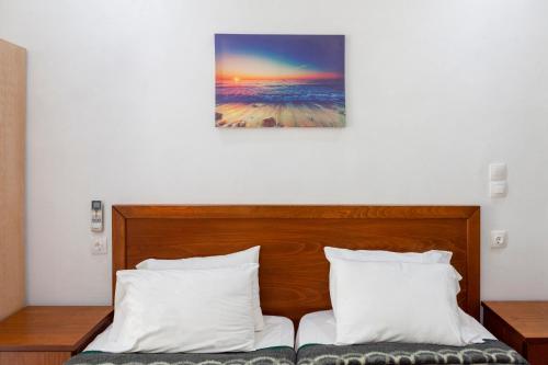 a bed with two pillows and a painting on the wall at Limani Apartments in Kassiopi