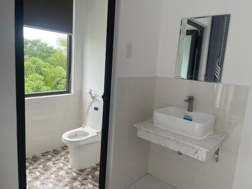 baño con aseo y lavabo y ventana en Moon house villa, en Hoi An