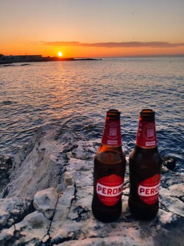 two bottles of beer sitting on a rock near the water at CASA ARCO BIANCO in Giovinazzo