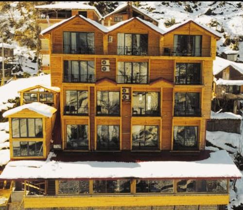 um grande edifício de madeira com neve em Yamacda Suit Otel em Çamlıhemşin