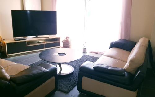 sala de estar con 2 sillas, mesa y TV en Grande maison près de Bordeaux Parking Pétanque WiFi en Beychac-et-Caillau