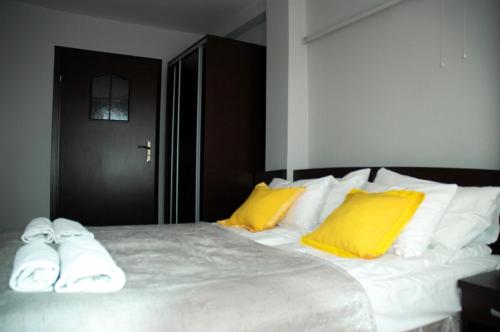 Un dormitorio con una cama grande con almohadas amarillas y blancas en Słoneczne Tarasy, en Mikołajki