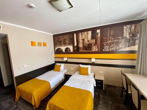 two beds in a room with yellow cushions at Hotel Vitalia in Boszkowo