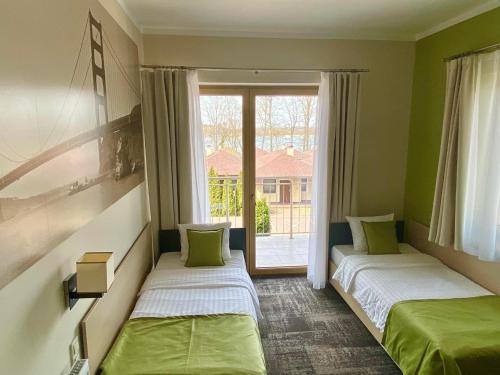 dwa łóżka w pokoju z oknem w obiekcie Hotel Vitalia w Boszkowie