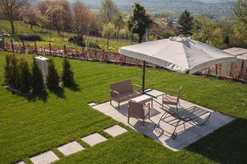 a patio with an umbrella and chairs on a lawn at Maison Lirà in Pren