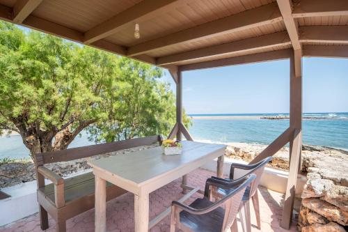 a table and chairs on a porch with the ocean at Mylos Seaside Experience in Frangokastello