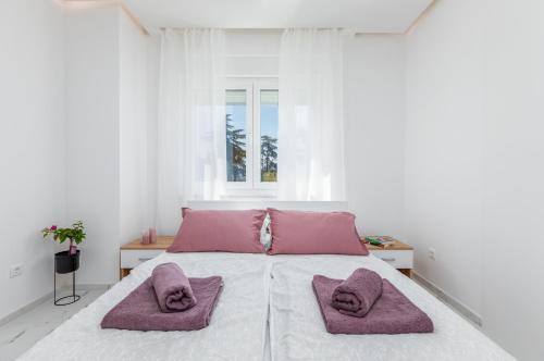 Biała sypialnia z dużym łóżkiem i różowymi poduszkami w obiekcie Apartman Knezevic A w Fažanie