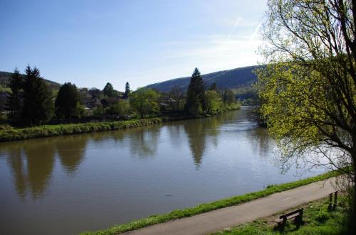 a river with a bench next to a road at Le Doux Rivage, proche de Charleville, jardin et accès à la voie verte in Joigny-sur-Meuse