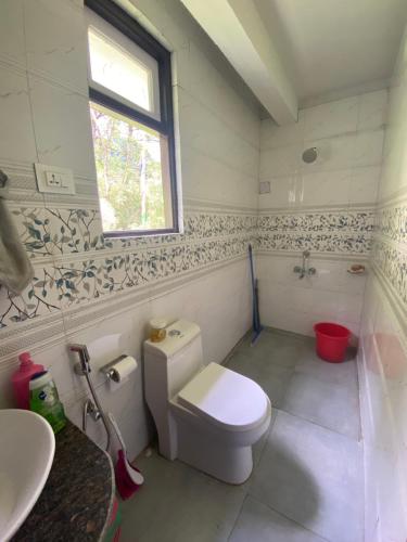 a bathroom with a toilet and a sink and a window at Hermit Retreat in Darjeeling