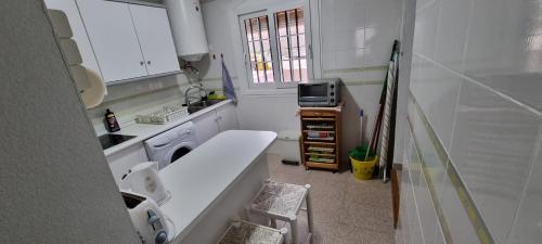 een kleine witte keuken met een wastafel en een magnetron bij MOJACAR PLAYA ADOSADO con piscina in La Marina de la Torre