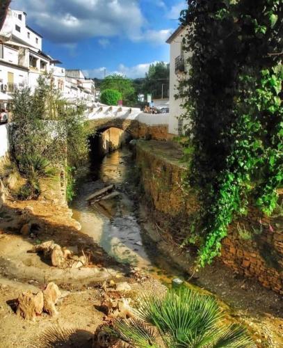 a small river in a town with a bridge at CASA ENROCADA in Setenil