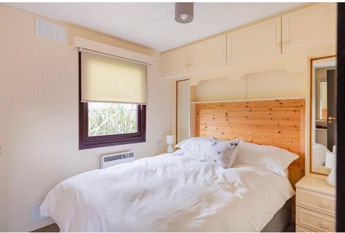 a bedroom with a large white bed with a window at Lodge Cabin with Fabulous Views - Farm Holiday in Stranraer