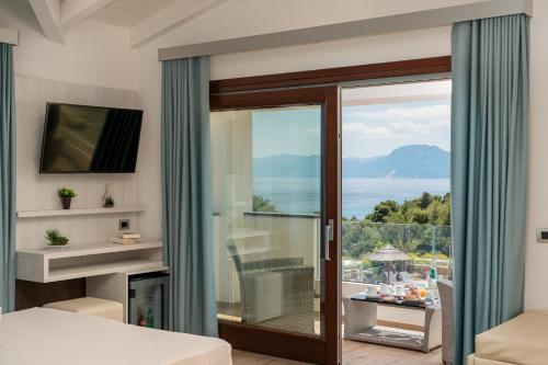 a bedroom with a sliding glass door with a view of the ocean at I Ginepri Hotel in Cala Gonone