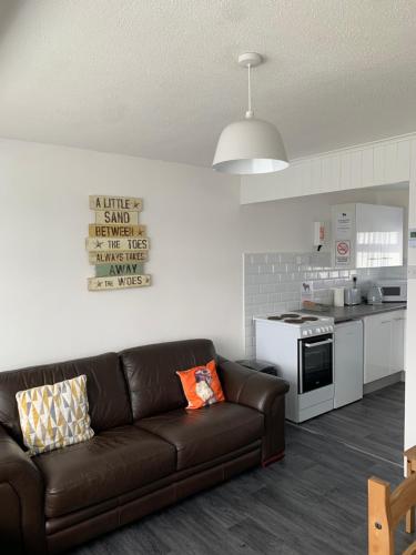 a living room with a brown couch in a kitchen at bulldog holidays 244 in Hemsby