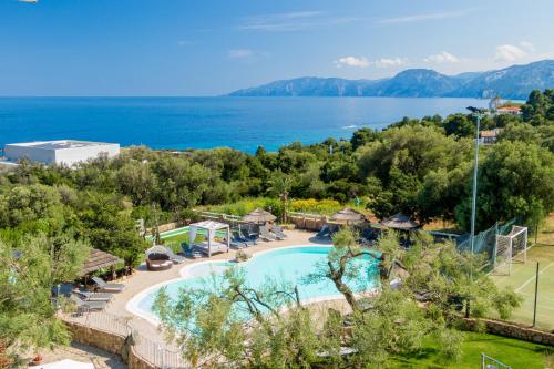 an outdoor swimming pool with a view of the water at I Ginepri Hotel in Cala Gonone