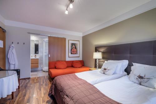 Snorri's Guesthouse في ريكيافيك: غرفة نوم بسرير واريكة برتقال