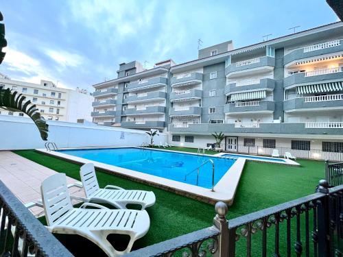 einem Pool mit zwei Gartenstühlen und einem Gebäude in der Unterkunft Sunny Escape in El Campello in El Campello