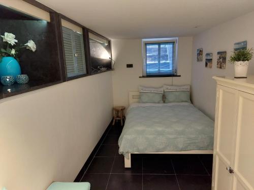a small bedroom with a bed and two windows at Zeelucht in Zandvoort