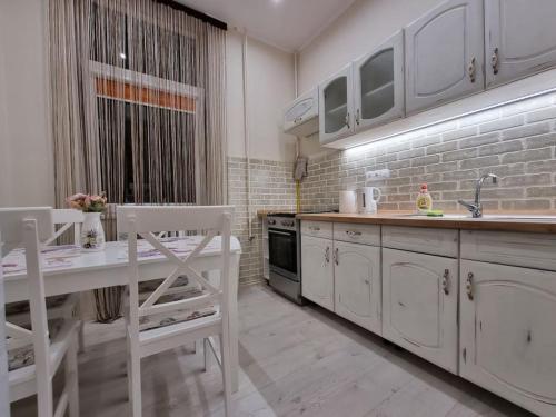 cocina con armarios blancos, mesa y fregadero en Vintage Apartman in city center, en Miskolc