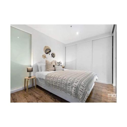 a bedroom with a large bed and a glass wall at Lovely apartment in Melbourne