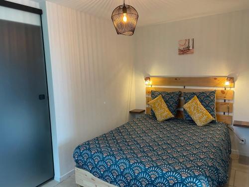 a bedroom with a bed with blue and yellow pillows at Studio Terrasse Vue Lac Entrée indépendante in Font