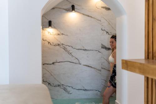 a woman standing in front of a marble wall at Amera Suites in Fira