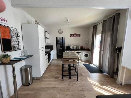 a kitchen and living room with a table and chairs at Spacieux Marx Dormoy avec parking gratuit C in Clermont-Ferrand