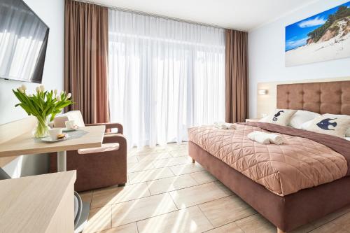 Habitación de hotel con cama, mesa y escritorio. en Villa Polna, en Grzybowo