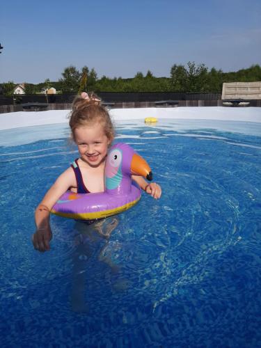 een klein meisje in het water in een zwembad bij Wichrowe Domki in Władysławowo