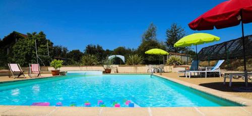 a swimming pool with two umbrellas and chairs at Le Pigeonnier @ Le Prielle in Madiran