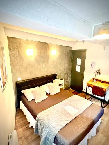 a bedroom with a large bed and a desk at Hôtel Paul Riquet in Béziers