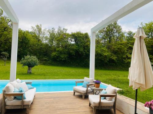 eine Terrasse mit Stühlen und einem Sonnenschirm neben einem Pool in der Unterkunft Villa Architecte Contemporaine Fuveau in Fuveau
