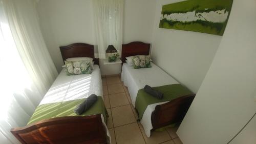 Habitación pequeña con 2 camas y ventana en Four Seasons Self-Catering Guest House, en Graskop