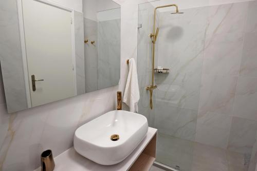 a white bathroom with a sink and a shower at Adonis Hotel Studios & Apartments in Naousa