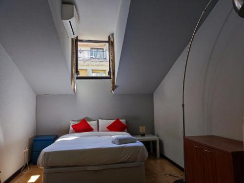 Un dormitorio con una cama con almohadas rojas y una ventana en Aparment Puerta de sol, en Madrid