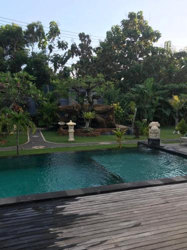 a swimming pool in a garden with a wooden deck at The Niti Hut's Lembongan in Nusa Lembongan