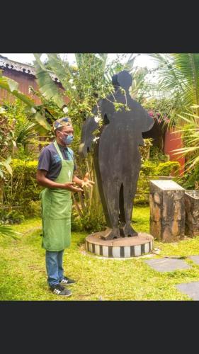 a man wearing a mask standing next to a statue at Roça Saudade Guest House in Trindade