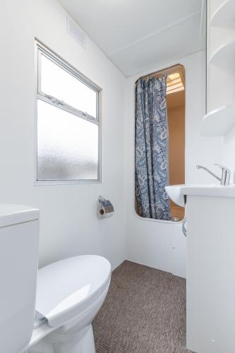a white bathroom with a toilet and a window at Atokaita in Palanga
