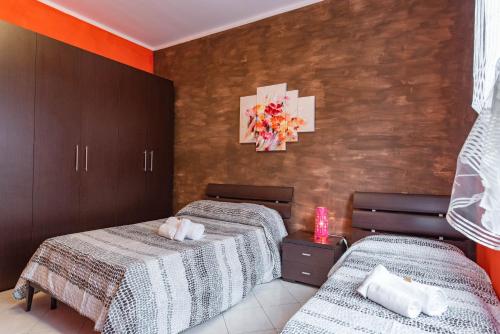 2 Betten in einem Zimmer mit orangefarbenen Wänden in der Unterkunft Casa Metro Lingotto in Turin