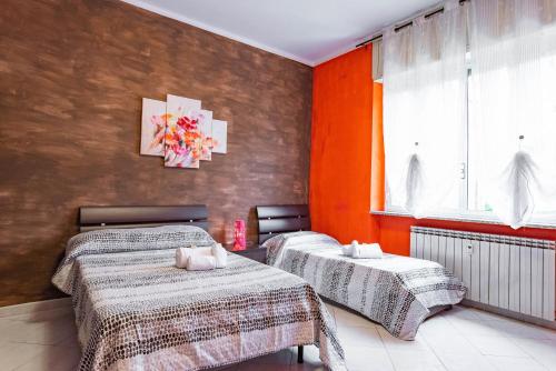 twee bedden in een kamer met oranje muren bij Casa Metro Lingotto in Turijn