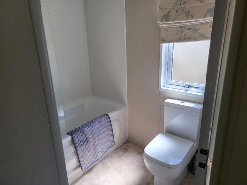 a small bathroom with a toilet and a bath tub at 2BR-Sleeps6-Fireplace-Parking-Patio-Seaside in Clacton-on-Sea