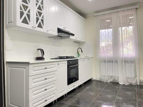 uma cozinha com armários brancos e um fogão preto em Spitak Tun em Ijevan