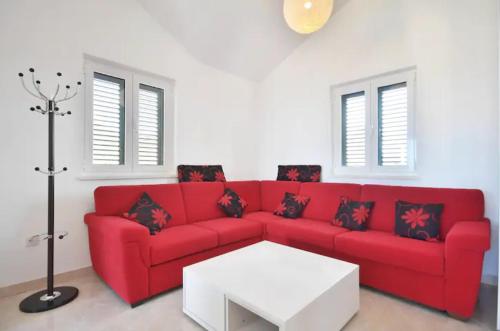 a living room with a red couch and a white table at Villa royale with shared pool in Hvar