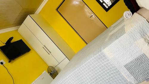 a bedroom with a bed with a yellow wall at Agnes Guest House in Germiston