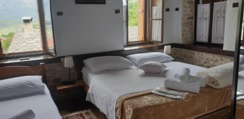 a bedroom with two beds with towels and windows at Silver Hill Guesthouse in Gjirokastër
