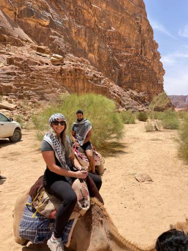 two people riding on the back of an elephant in the desert at Wadi Rum Magic Camp in Wadi Rum